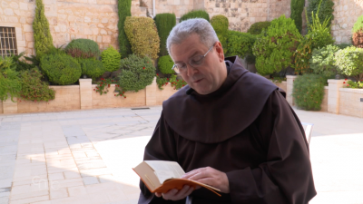 Fr. Francesco Patton prega all'aperto leggendo la Bibbia