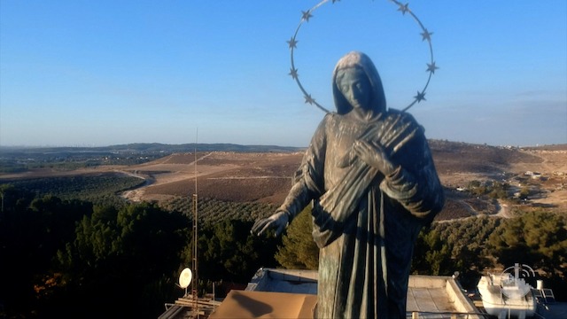 Statua della Madonna di Palestina con sfondo del cieloe campi coltivati